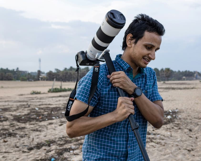 travel photographer holding a tripod as he walks onto shoot