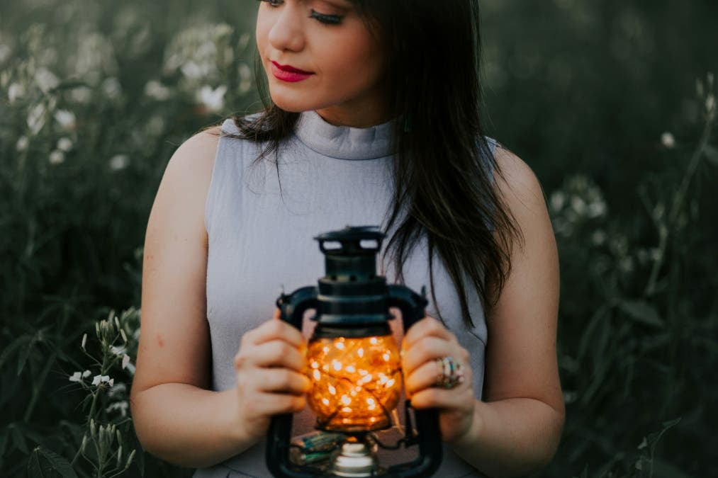 portrait of girl holding a lamp close to her cheat