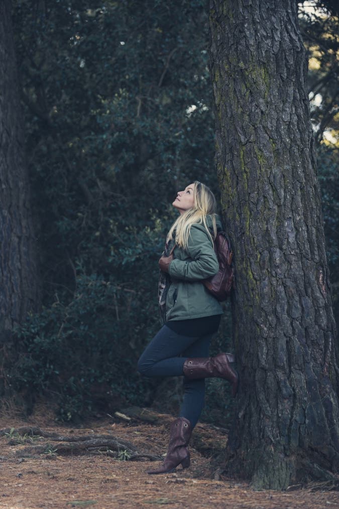 blonde girl posing against a tree