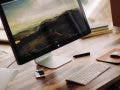 picture of wooden desk with Mac monitor and magic keyboard