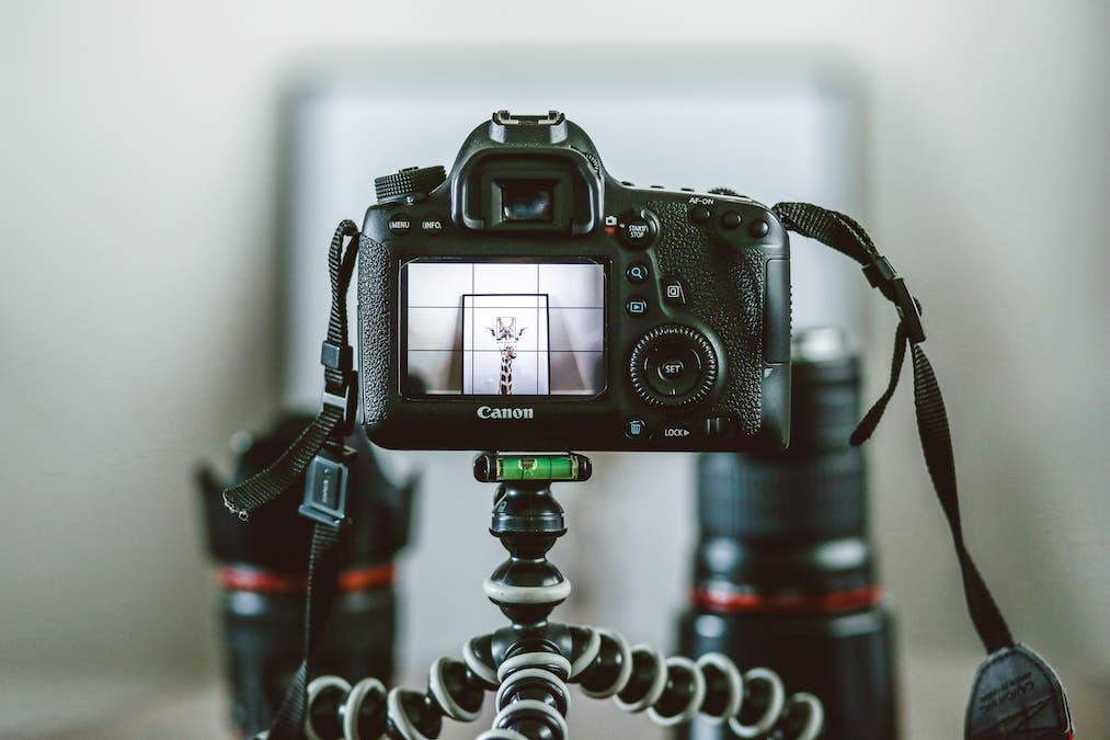 tripod holding a camera with lenses displayed behind it