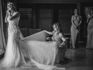 a wedding entourage helps the bride with her dress